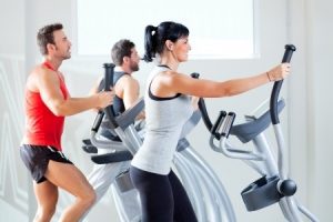 People exercising on stride machines in a gym.