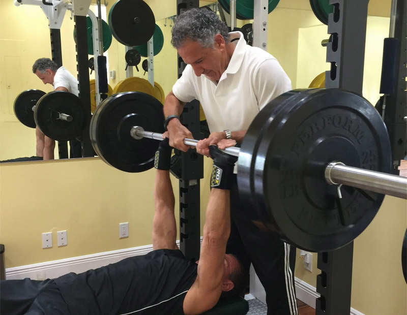 Frank Manganella spotting for a client doing a bench press.