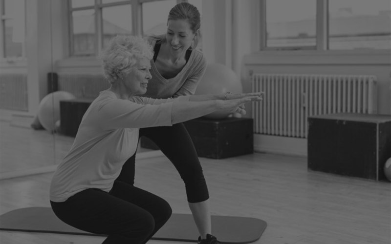 Injury Prevention - Trainer helping a client do a squat.